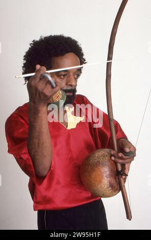 Portrait posé en 1983 de Nana Vasconcelos, percussionniste de jazz brésilien, jouant du berimbau, un instrument de gourde à une seule corde. A Manhattan. Banque D'Images