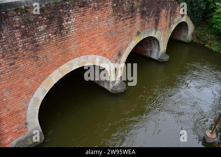 L'eau coule sous le pont de briques du Smedenpoort, l'une des portes médiévales de la ville entourant le centre-ville de Bruges Banque D'Images