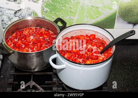La confiture juteuse de fraises sucrées est cuite dans des casseroles. Préparations pour l'hiver. Banque D'Images