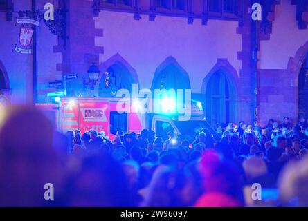 24 décembre 2023, Hesse, Francfort-sur-le-main : une ambulance traverse les visiteurs sur la Römerberg avec ses lumières bleues clignotantes pendant la sonnerie de la cloche de la ville. Pendant la sonnerie traditionnelle de la cloche de Francfort la veille de Noël, environ 50 cloches des églises du centre-ville peuvent être entendues simultanément. Photo : Andreas Arnold/dpa Banque D'Images