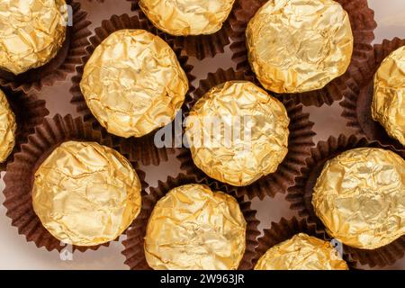 Plusieurs chocolats sur un plat en céramique blanche, macro, vue de dessus. Banque D'Images