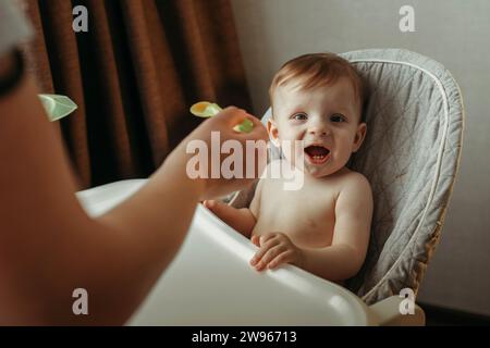 Un petit enfant mange de la purée de légumes. Maman nourrit le bébé. Banque D'Images