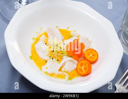 Gros plan de délicieux ceviche de fruits de mer de chinchard avec sauce à l'avocat épicée, légumes verts et cumquat Banque D'Images