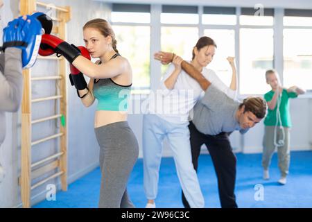 Adolescente travaille sur la force et la vitesse des mitaines de punch de boxe avec l'aide du partenaire masculin dans les pattes de boxe. L'homme joue le rôle de cible et mannequins duri Banque D'Images