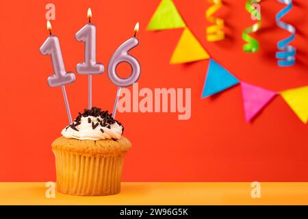 Gâteau d'anniversaire avec bougie numéro 116 - fond orange pétillant avec bandoulière Banque D'Images