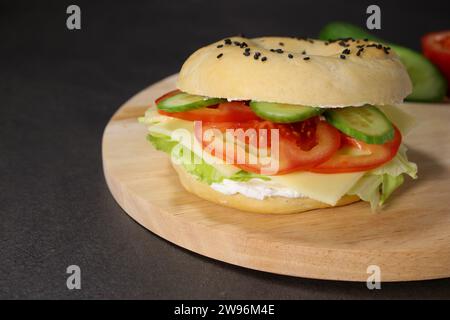 Délicieux bagel au fromage végétalien, légumes frais sur plaque en bois Banque D'Images