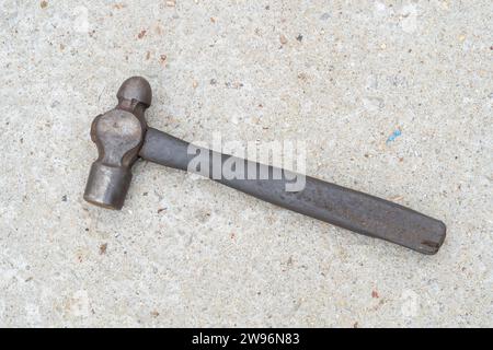 Un seul vieux marteau en métal ou en fer sale avec poignée en bois est posé sur le sol en béton. Pose à plat Banque D'Images