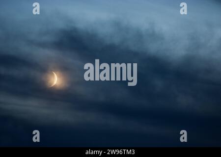 La lune de Heavenly Crescent glisse à travers le ciel orageux à l'approche du soir Banque D'Images