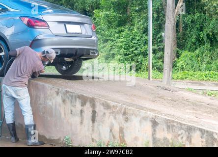 Photo du personnel ou laveur de voiture au centre de service de soins de voiture lave une voiture du client à l'aide d'un pistolet à eau à haute pression pour arroser une voiture vers le bas avec copie spa Banque D'Images