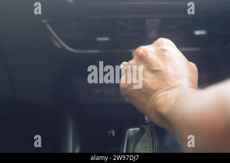 la main du conducteur tient le levier de vitesse automatique pour changer de vitesse tout en étant assis sur le siège du conducteur de la voiture et conduisant une voiture de super sport de luxe. Gros plan Banque D'Images