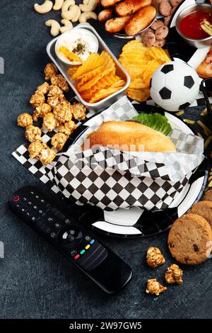 Graisses saturées. L'heure du football. Télécommande TV et collations - chips, pop-corn, biscuits, fromage, sauce, frites, burger, noix. Vue de dessus Banque D'Images