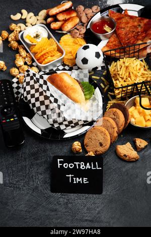 Graisses saturées. L'heure du football. Télécommande TV et collations - chips, pop-corn, biscuits, fromage, sauce, frites, burger, noix. Vue de dessus Banque D'Images