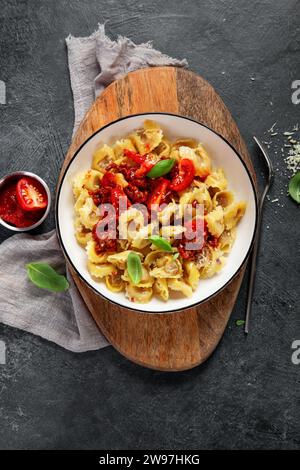 Cuisine italienne traditionnelle. Plat avec ravioli, tomate, tomates séchées, bases et fromage râpé. Pâtes savoureuses. Vue de dessus Banque D'Images