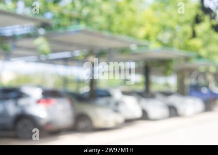 Les voitures sont stationnées sur le parking avec toit dans la zone ouverte en face du bureau, de l'université, de l'école ou de l'hôpital le jour ensoleillé. Photo floue Banque D'Images