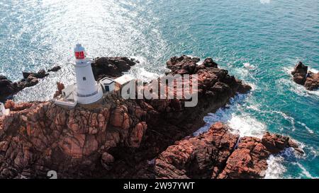 Une vue aérienne panoramique du phare de la Corbière perché au sommet d'une falaise spectaculaire à Jersey Banque D'Images