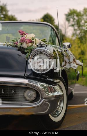 Une voiture vintage garée avec des fleurs sur le côté de la rue Banque D'Images