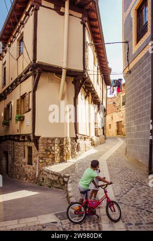 Enfants jouant avec un vélo rouge à Poza del Sal (Castille-et-León, Espagne) Banque D'Images