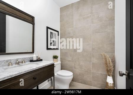 Une toilette blanche et un lavabo blanc contre un mur carrelé dans une salle de bain, Banque D'Images