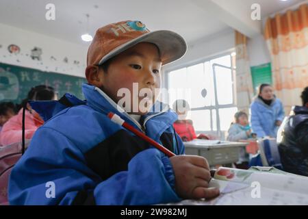 Jishan, province chinoise du Gansu. 25 décembre 2023. Les élèves fréquentent une classe dans une école primaire du canton de Liugou, dans le comté de Jishan, dans la province du Gansu, au nord-ouest de la Chine, le 25 décembre 2023. Les écoles primaires et secondaires dans les zones de Jishishan touchées par le séisme ont commencé à reprendre les cours lundi après un contrôle de sécurité. Crédit : Fang Xin/Xinhua/Alamy Live News Banque D'Images