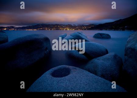 Les rochers de granit reposent alors que Incline Village illumine les nuages, Lake Tahoe, Nevada. Banque D'Images