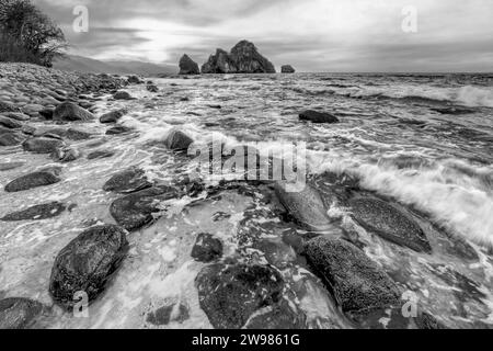 Un magnifique coucher de soleil océanique avec Une vague se brisant sur le rivage haute résolution Noir et blanc Banque D'Images