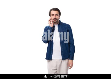 jeune surpris beau brun brutal caucasien mec est habillé avec désinvolture dans une chemise et un pantalon Banque D'Images