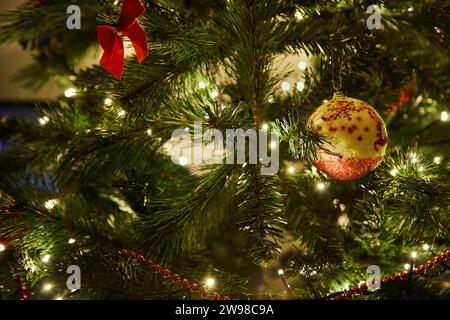 Gros plan d'un sapin de Noël magnifiquement décoré avec des ornements colorés, une guirlande scintillante et des lumières brillantes, créant un cadre festif et magique Banque D'Images