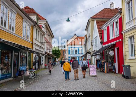 Bergen, Norvège, le 22 juin 2023 : un groupe de personnes marche sur une rue pavée vacante dans le centre-ville de Bergen après une tempête de pluie. Le Hollenderga Banque D'Images