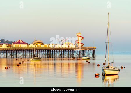 Port de Herne Bay juste après le lever du soleil. Yacht avec la jetée derrière, le tout baigné dans la lumière du lever du soleil. Ciel une couleur rose bleu pastel. Mer très calme. Banque D'Images