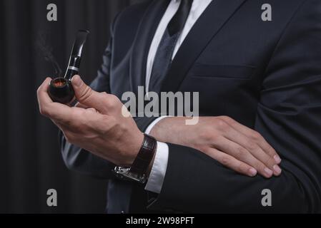 Image de mains masculines tenant une pipe à fumer. Concept de tabagisme. Supports mixtes Banque D'Images