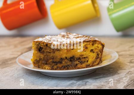 Un morceau coupé de tarte à la citrouille maison dans une soucoupe sur la table de la cuisine dans un éclairage chaud Banque D'Images