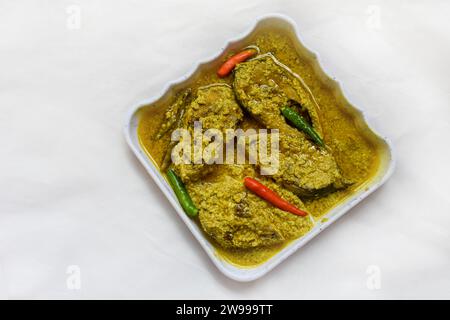 Une assiette blanche avec un délicieux assortiment de poissons hilsa recouverts de piment vert aromatique Banque D'Images