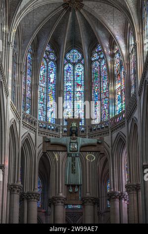 Intérieur de la cathédrale Saint-Julien du Mans, croix de Jésus au-dessus de l'autel devant le vitrail Banque D'Images