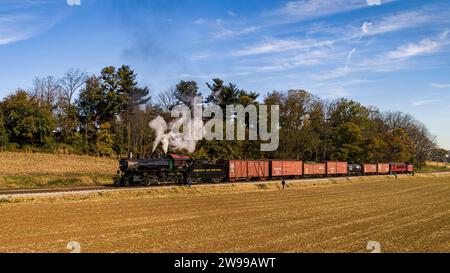 Une vue aérienne d'un train de passagers à vapeur antique soufflant de la fumée et de la vapeur, alors qu'il parcourt lentement les terres agricoles un jour d'automne Banque D'Images