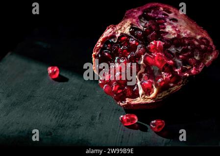 Une grenade rouge isolée sur fond de bois noir, gros plan, photographie de nature morte Banque D'Images