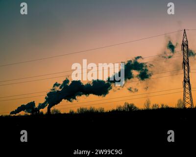 Vue aérienne de la centrale au charbon de tuyaux hauts avec fumée noire se déplaçant vers le haut de l'atmosphère polluante au coucher du soleil. Banque D'Images