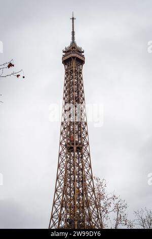 Branches d'automne sur la Tour Eiffel à Paris avec son ascenseur rouge montant - France Banque D'Images