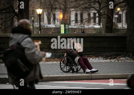 New York, États-Unis. 24 décembre 2023. Un homme en fauteuil roulant tient un carton et supplie de l'aide à New York, aux États-Unis, le 24 décembre 2023. Les difficultés que connaissent de nombreux Américains depuis l’ère COVID-19 ont maintenant pris de l’ampleur, alors que l’automne de Noël lundi a renforcé la frénésie de shopping mais a accablé les gens ordinaires avec la pression croissante de la vie au milieu de l’inflation persistante. Crédit : Michael Nagle/Xinhua/Alamy Live News Banque D'Images