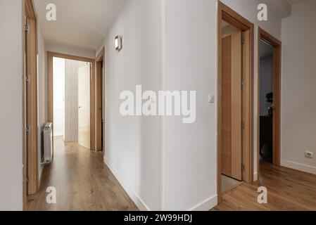 Couloir dans une maison avec des planchers de bois clair et des portes en chêne français à d'autres pièces et des murs blancs simples Banque D'Images