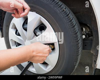 homme remplissant la pression d'air dans le pneu de voiture gros plan Banque D'Images