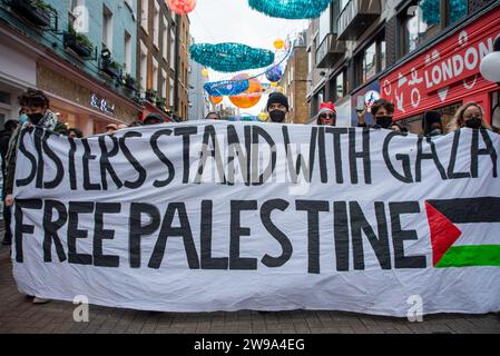 Londres, Royaume-Uni. 23 décembre 2023. Des manifestants brandissent une bannière le long de la rue Carnaby pendant la manifestation. Un groupe féministe appelé Sisters Uncut a organisé une manifestation, la veille du soir de Noël. Il a été appelé «Arrêter Noël pour la Palestine» pour montrer sa solidarité avec la Palestine pendant la période de Noël. (Image de crédit : © Krisztian Elek/SOPA Images via ZUMA Press Wire) USAGE ÉDITORIAL SEULEMENT! Non destiné à UN USAGE commercial ! Banque D'Images