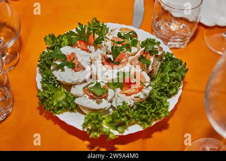 Table de fête du nouvel an magnifiquement arrangée avec paniers de fromage, saumon frais et verts vibrants, créant une atmosphère élégante et accueillante Banque D'Images