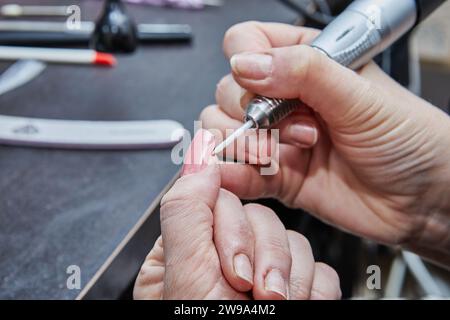 Témoin de l'expertise d'un technicien d'ongles comme ils appliquent habilement des extensions d'ongles de gel, polir les ongles savamment, et utiliser une machine de manucure à crea Banque D'Images