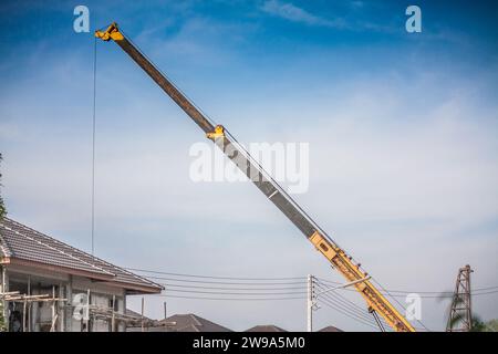 bras télescopiques jaunes de camion de grue de construction mobile soulevant la dalle de béton à la maison de construction au chantier de construction Banque D'Images