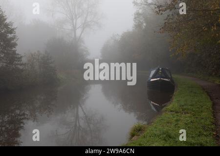 Un paysage atmosphérique donnant sur un canal. L'image a été prise un matin brumeux, un bateau étroit amarré au premier plan et un pont au loin Banque D'Images