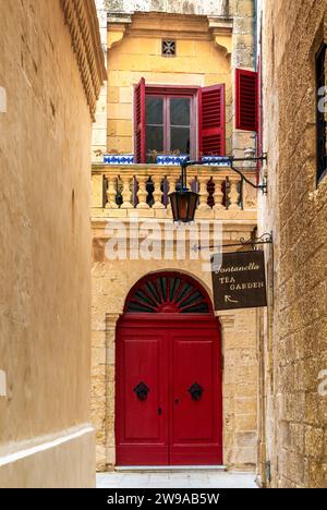 Mdina, Malte - 22 décembre 2023 : ruelle étroite dans la vieille ville de Medina avec restaurant et porte colorée Banque D'Images