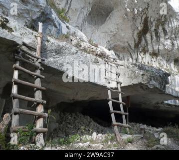 ancienne grotte creusée dans la roche utilisée dans la préhistoire par les hommes primitifs comme abri et reproduction de deux échelles en bois Banque D'Images