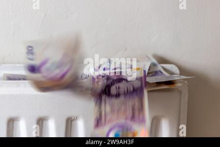 Un concept britannique de chauffage, coût de l'énergie avec une pile de billets de banque de 20 livres sterling montant du haut d'un radiateur de chauffage central, donnant l'imprimeur Banque D'Images