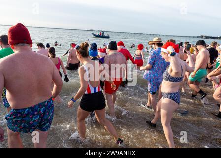 Jubilee Beach, Marine Parade, Southend on Sea, Essex, Royaume-Uni. 26 décembre 2023. Comme c'est devenu une tradition en bord de mer, un « Boxing Day DIP » a eu lieu dans l'estuaire froid de la Tamise à Southend on Sea, près de l'embarcadère de la ville, pour recueillir des fonds pour l'association caritative locale de la Royal National Lifeboat institution. Près de 700 personnes ont pris l'eau qui a été mesurée à 7,2 degrés Celsius. Beaucoup de nageurs courageux portaient des costumes de Noël festifs. Les équipages de la RNLI étaient présents pour superviser la sécurité. Courir dans la mer Banque D'Images