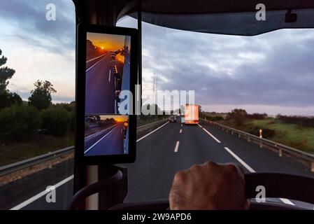 Vue depuis la position du conducteur d'un camion sur la route d'un lever de soleil vu par la caméra de vision arrière du véhicule. Banque D'Images